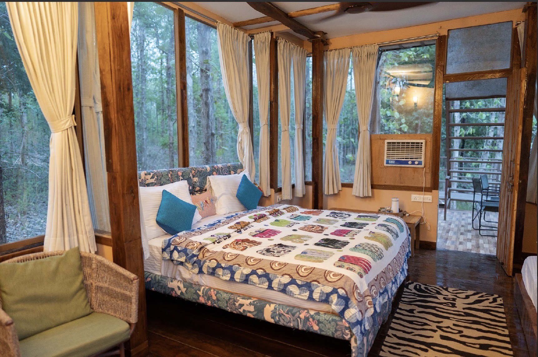 Forest cabin bedroom with large windows and colourful bedding